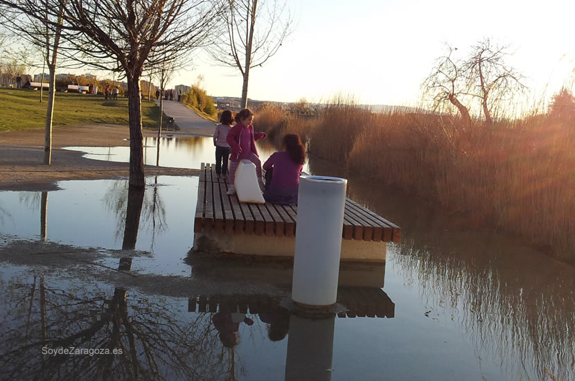 Niñas jugando en un banco rodeado de agua junto al embarcadero del Parque del Agua de Zaragoza